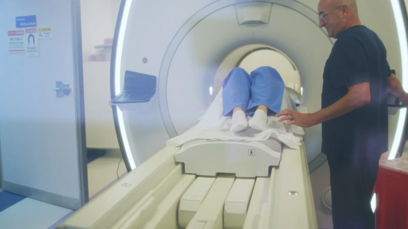 A SimonMed technologist guides a patient on the table into the bore of an MRI scanner